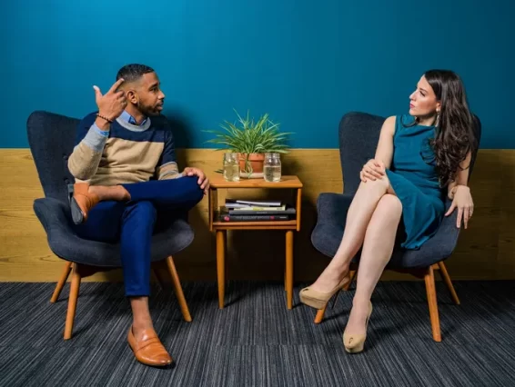 woman-wearing-teal-dress-sitting-on-chair-talking-to-man-2422280-680w